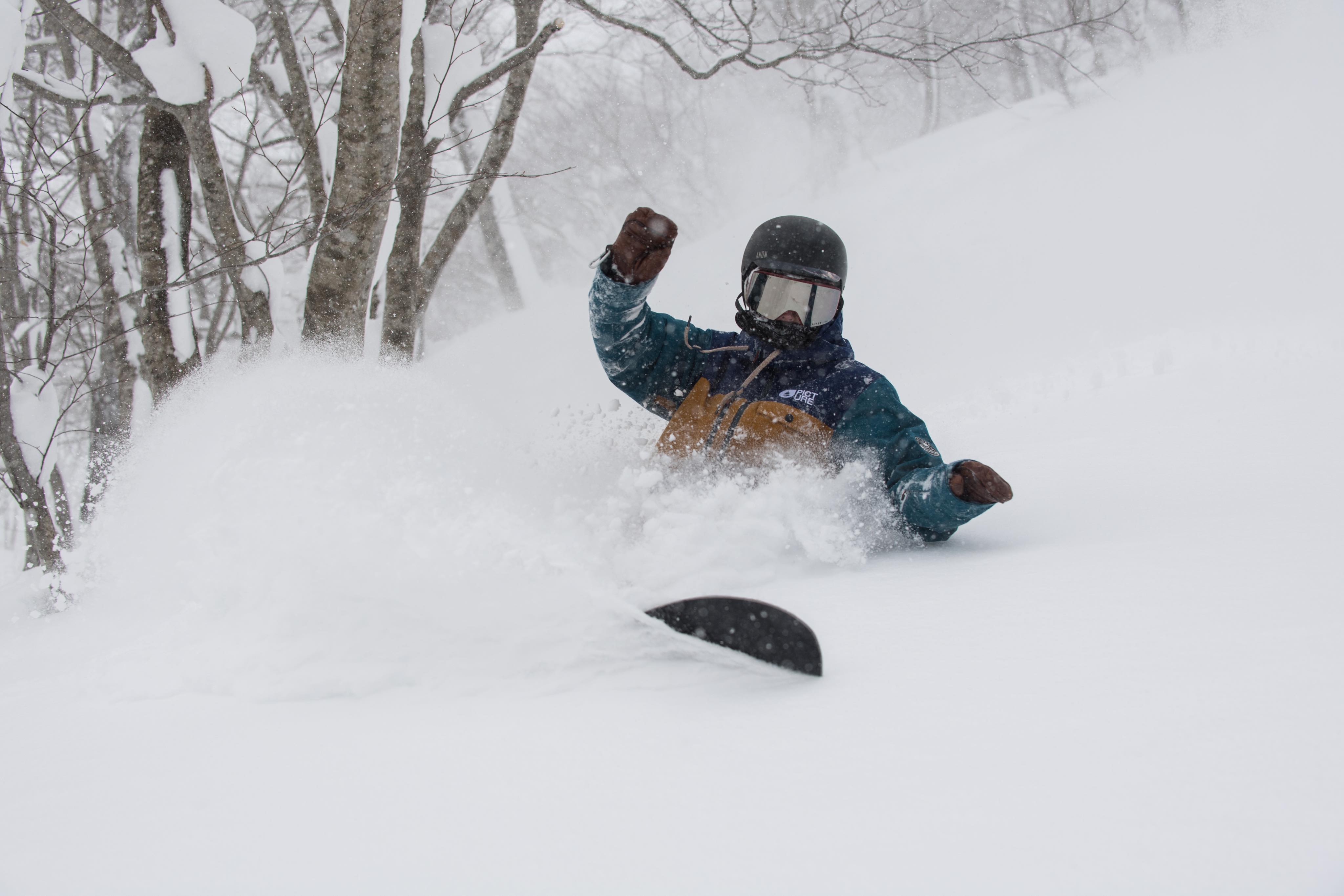 Snowboarder riding through deep powder snow in Japan