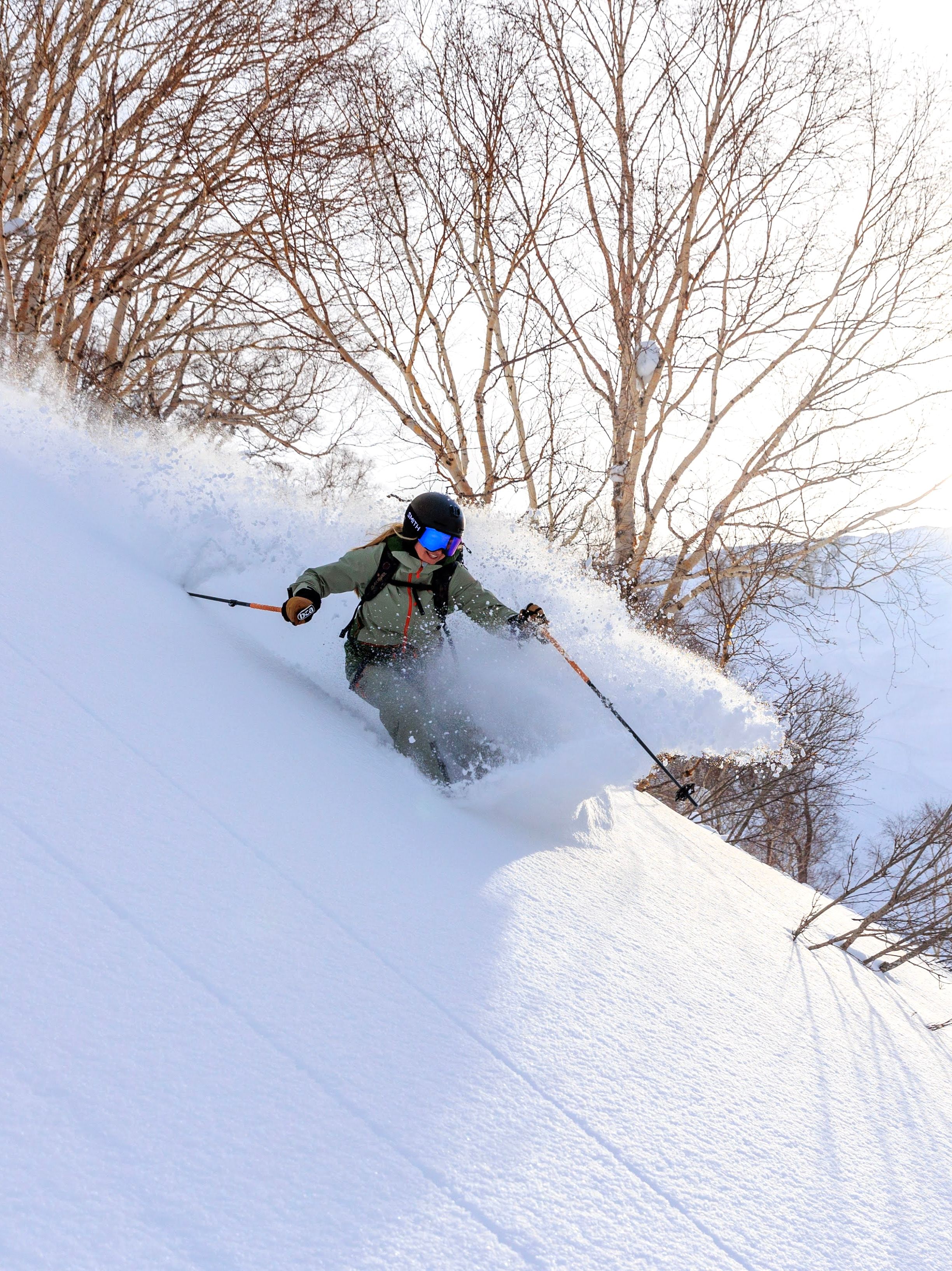 Skier carving a turn through fresh powder, with snow spraying into the air